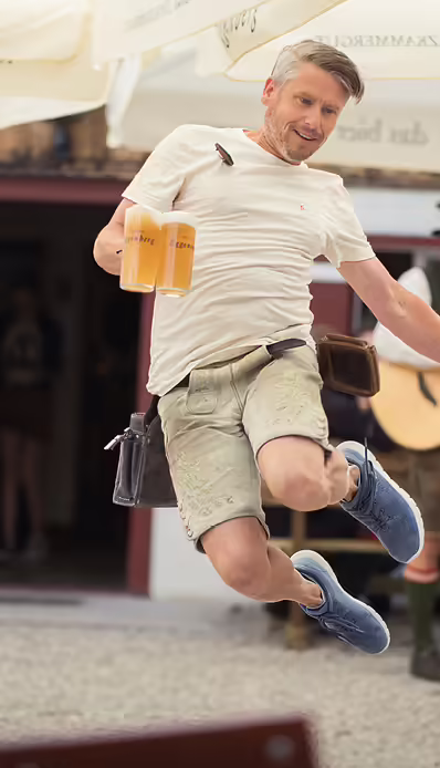 Mann springt mit zwei Biergläsern