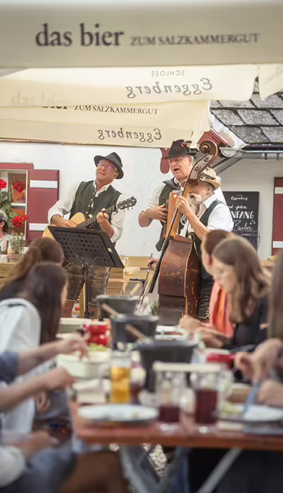 Musiker spielen im Freien, Gäste essen.